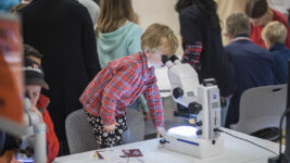 En liten pojke tittar i ett mikroskop under ForskarFredag i Umeå